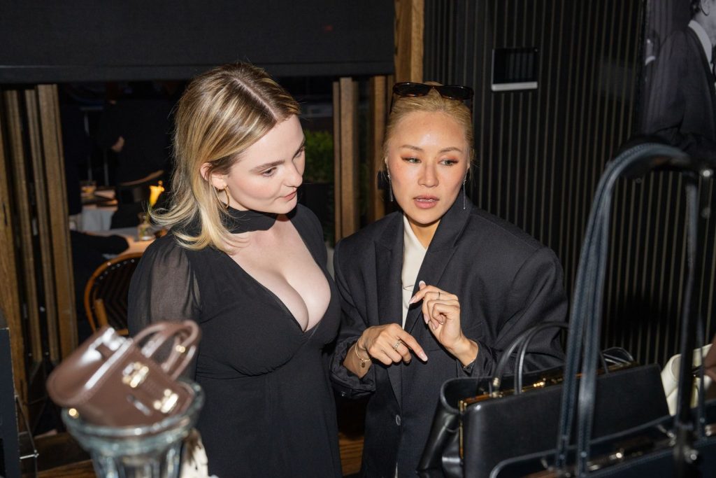 Morgan Lily and an Asian girl looking at a purse at a party