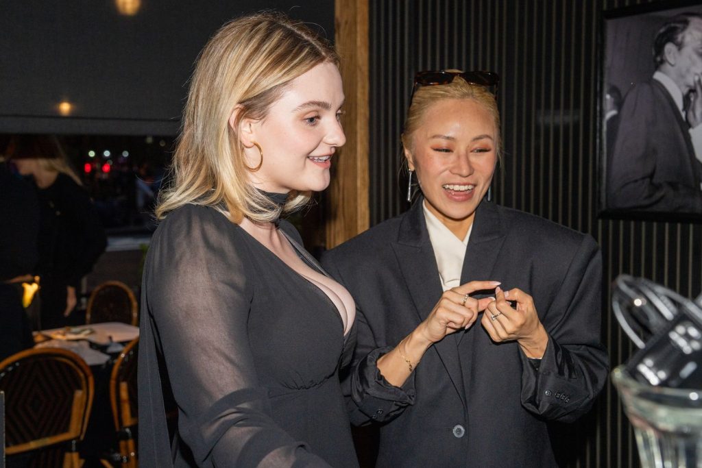 Side view of Morgan Lily and an Asian girl looking at a purse at a party