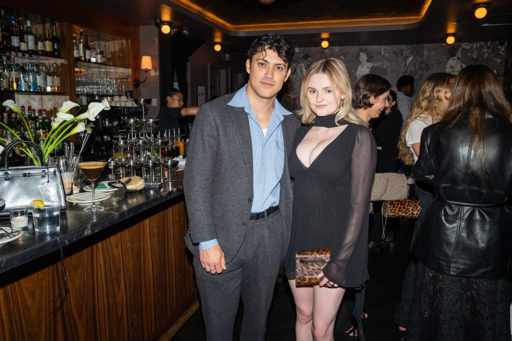 Morgan Lily in a sexy black dress next to a man in a suit at a party