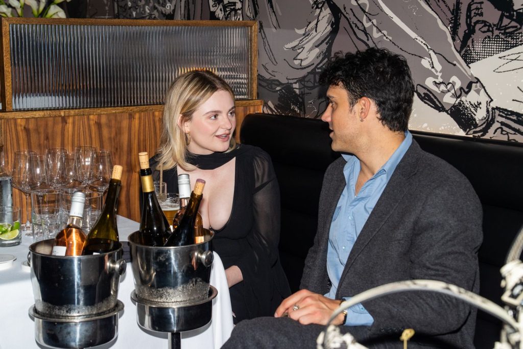Morgan Lily sitting down at a dinner party and having a conversation with a man