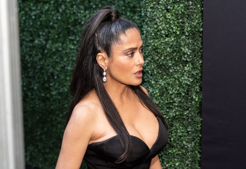 Close up of Salma Hayek walking onto a red carpet in a black dress