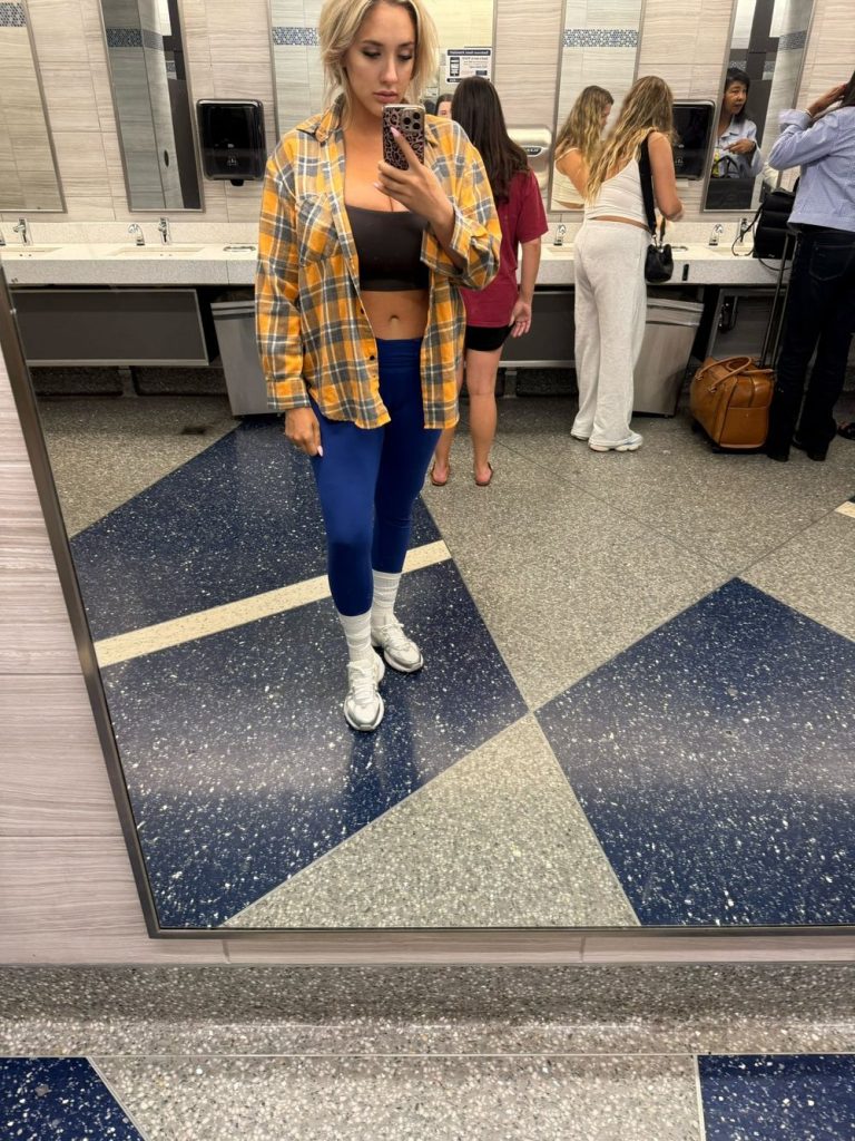 Sara Blake Cheek selfie from the airport showcasing the sports bra she was told to cover up