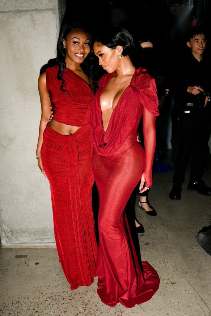 Saweetie posing next to another woman wearing a sexy red dress