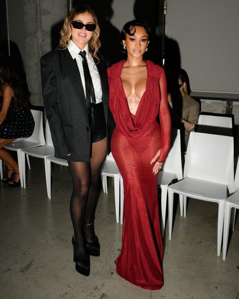 Far away view of Saweetie posing next to a woman dressed in a school outfit