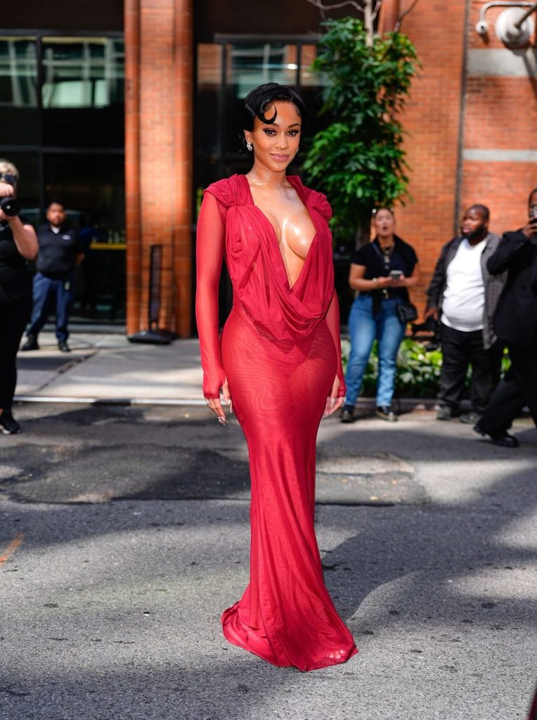Front view of Saweetie in a deep plunging red dress