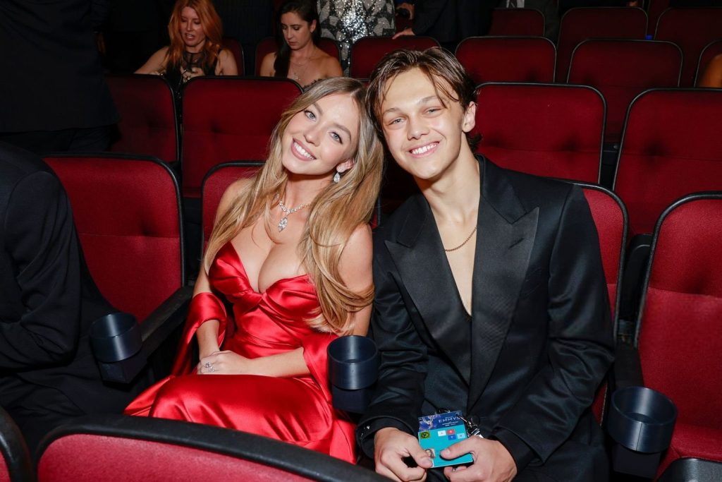 Sydney Sweeney sitting down with a big smile on her face next to a man at the Emmys