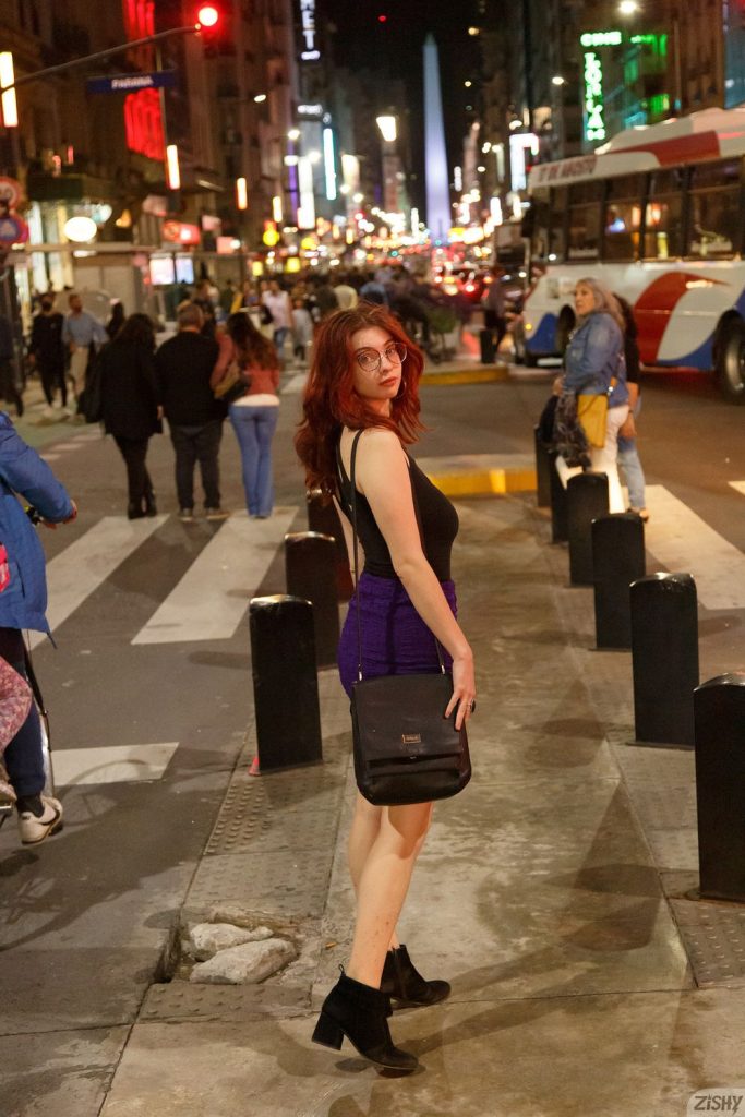 Redhead looks back while on a busy sidewalk wearing a nice dress