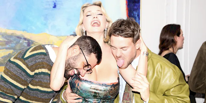 Two men putting their heads close to big tit blonde's cleavage at a party