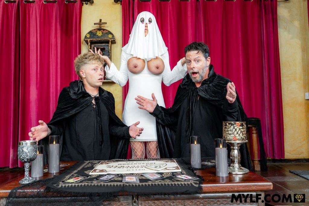 Topless ghost woman stands between two men in robes all throwing their hands up in surprise