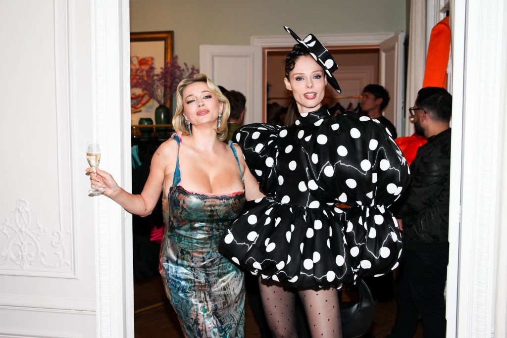 Caroline Vreeland showing big boob cleavage in a nice dress while posing next to a woman in a wacky polka dot dress