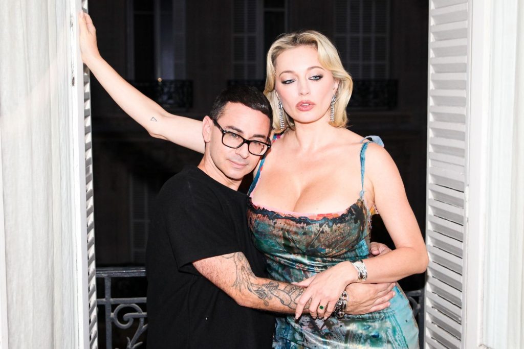 Close up of short man placing his head close to Caroline Vreeland's big boobs
