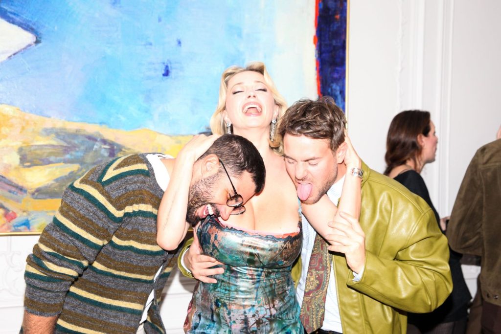 A couple of guys pretending to lick Caroline Vreeland's big boobs at a party