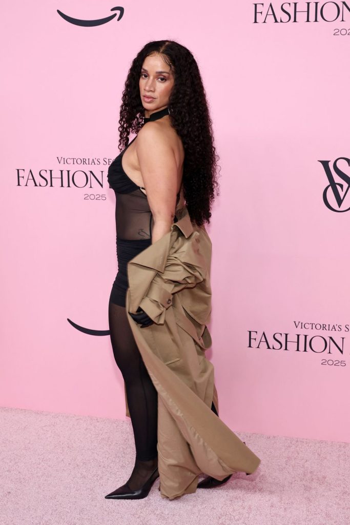 Dascha Polanco letting her coat drag while she is posing to the side
