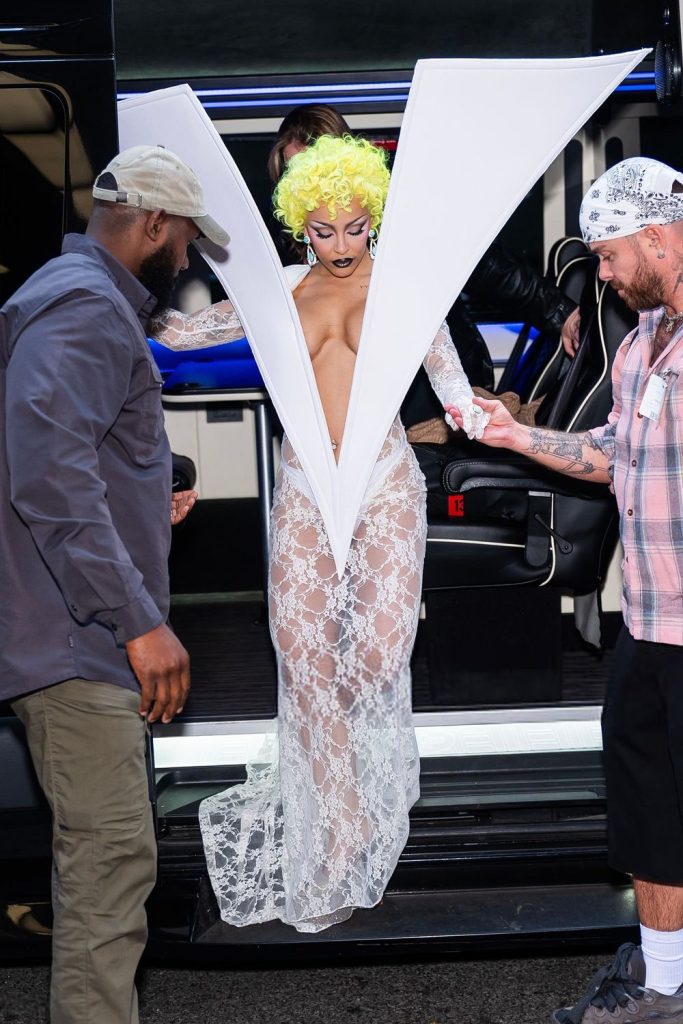 Doja Cat getting help while wearing a dress shaped like a tall V