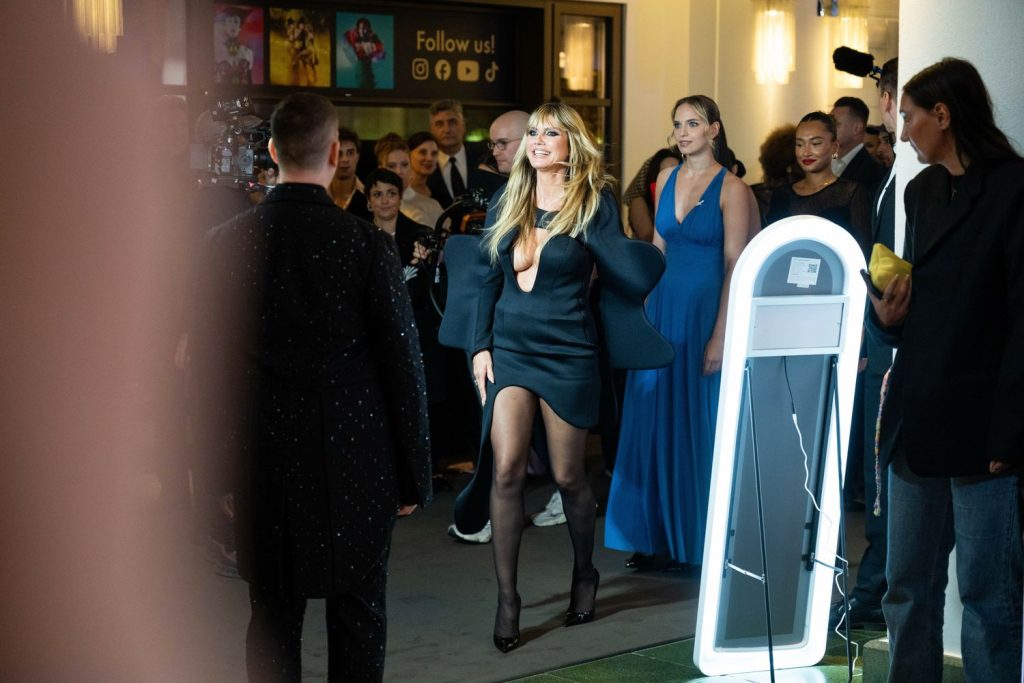 Heidi Klum walking onto the red carpet wearing a sexy dress and pantyhose