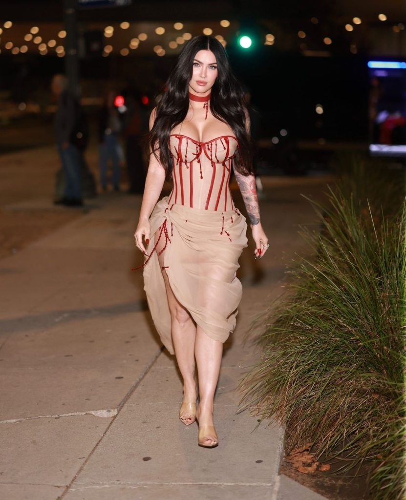 Megan Fox look directly into the camera as she walks along the walkway