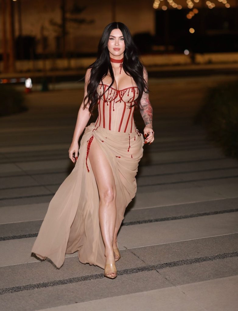 Megan Fox showing leg while walking along a walkway