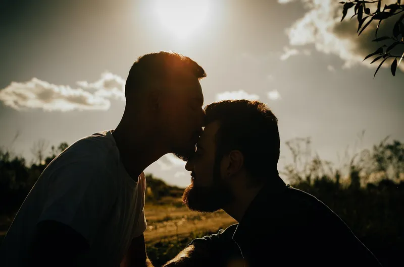 Male couple with one kissing the other on the forehead
