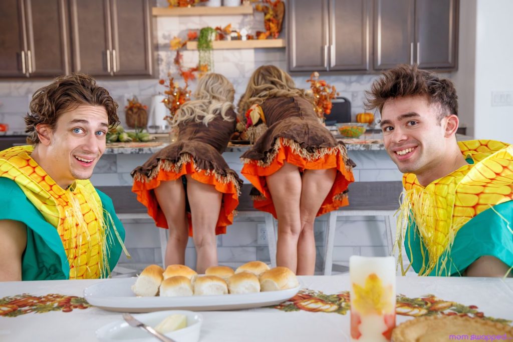 Horizontal of two guys looking into the camera while two bent over women stand in the background