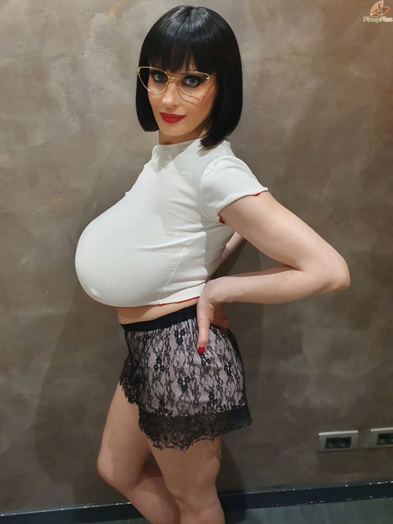 Closer side view of woman with large breasts posing in a tight top