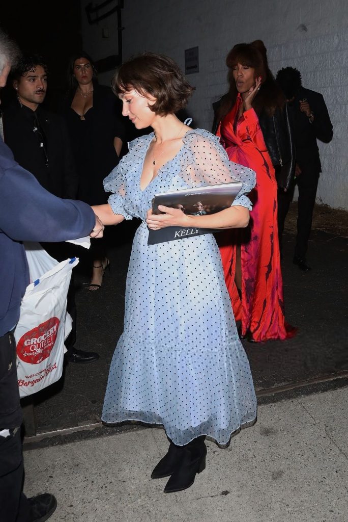 Full body side view of Milana Vayntrub signing an autograph