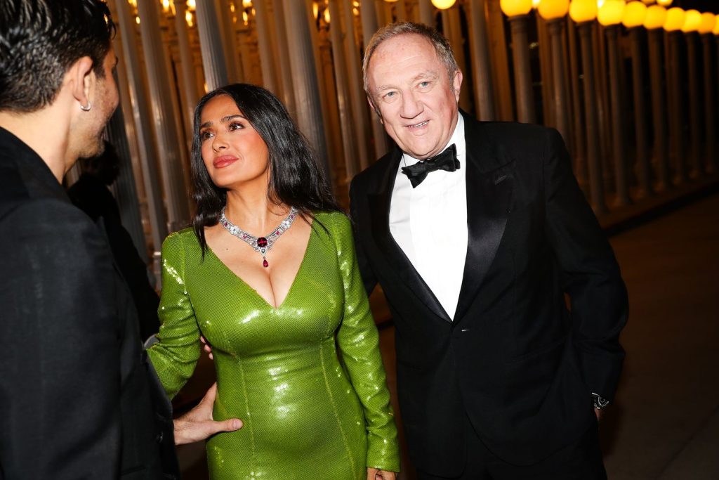 Close up of Salma Hayek greeting another man with her husband standing beside her