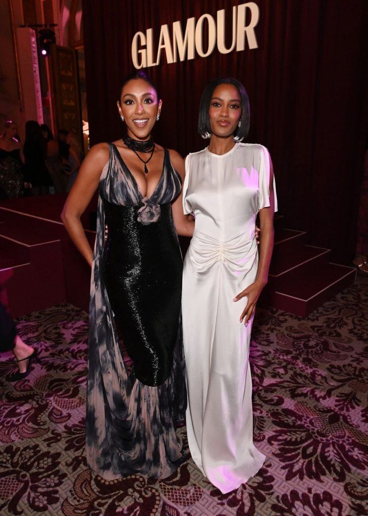 Full body front view of Tayshia Adams and another woman posing next to each other