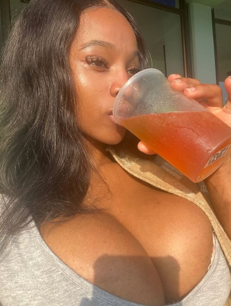 Close up of black girl drinking from a plastic cup and her big breasts