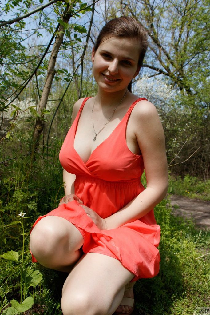 Frontal of woman smiling while sitting on her knees in the grass
