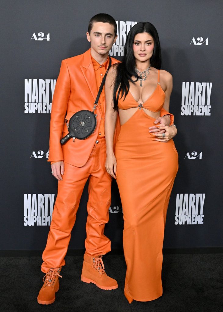 Frontal full body view of Kylie Jenner and Timothée Chalamet posing on a red carpet next to each other in matching outfits