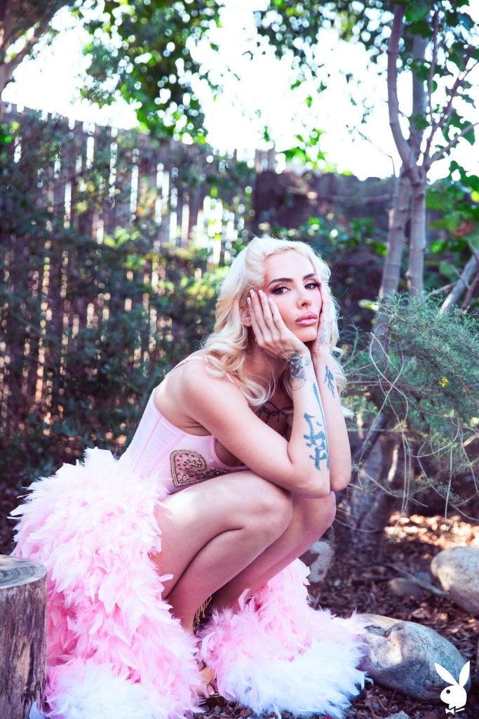 Frontal of woman squatting down in a backyard with her head resting in her hands wearing a pink princess dress