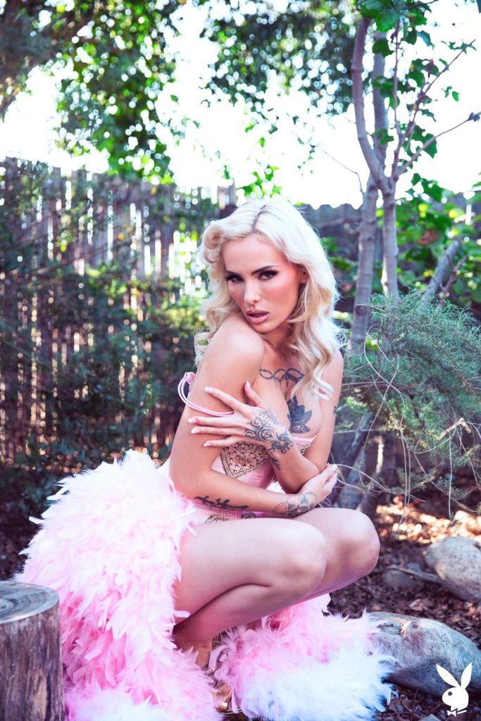 Frontal of woman squatting down in a backyard with her arms wrapped around her chest wearing a pink princess dress