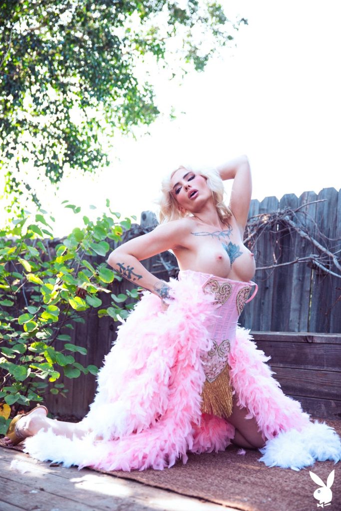 Frontal view of topless woman sitting on her knees with one arm above her head