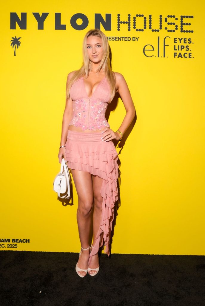 Far away view of blonde woman in a dress posing against a yellow background