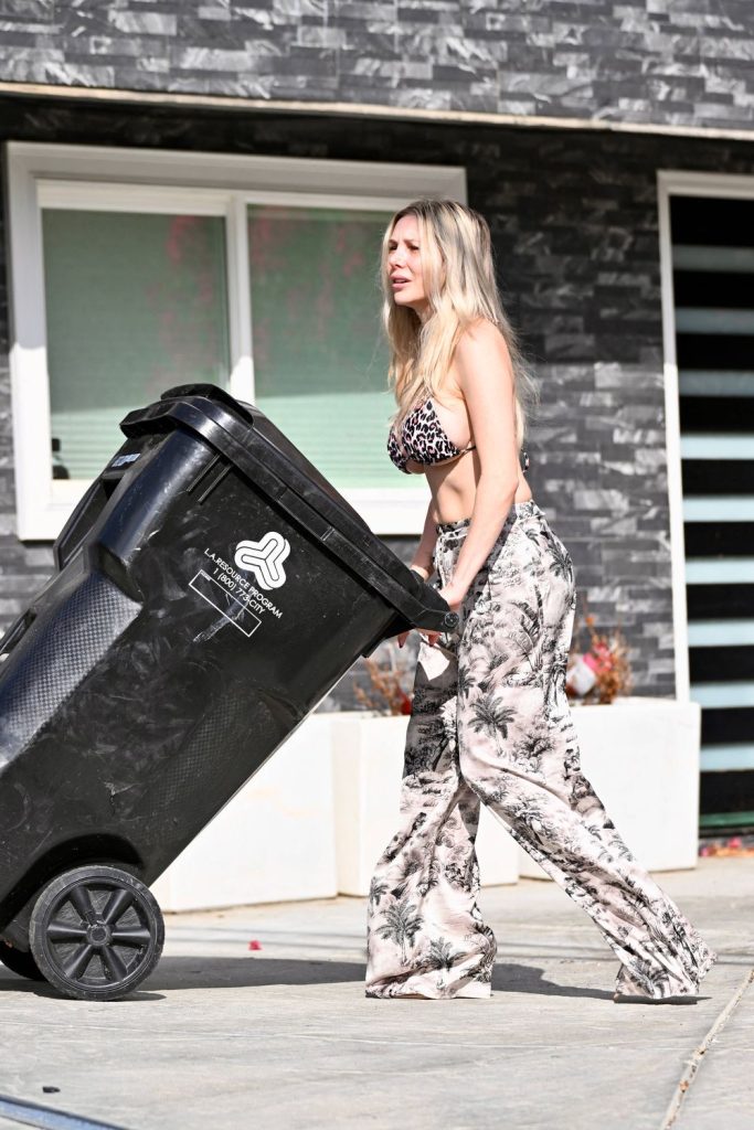 Full body side view of girl in a bikini top pushing her garbage bin