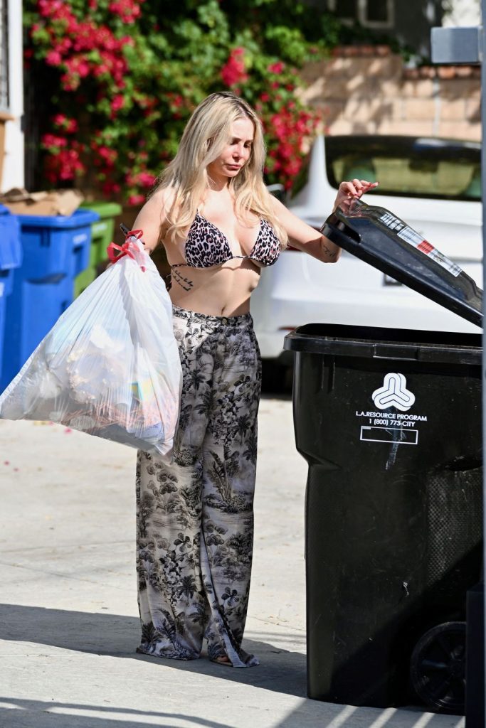 Frontal far away view of girl opening the lid of a garbage bin