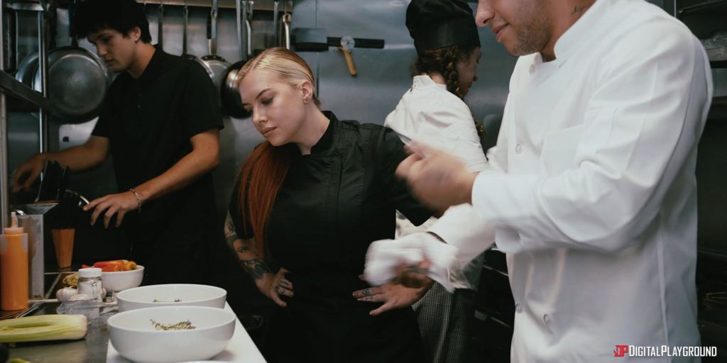Female chef with a stern look inspects dishes in a kitchen