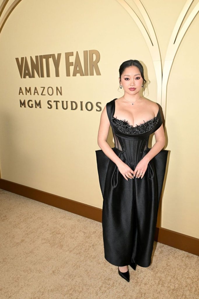 Full body frontal of Asian woman standing in front of a sign that says VANITY FAIR