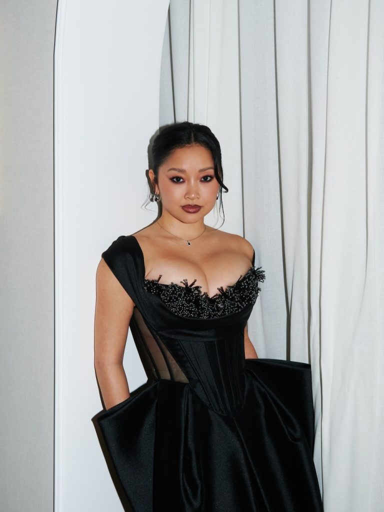 Close up of Asian woman standing at a slight angle in front of a curtain