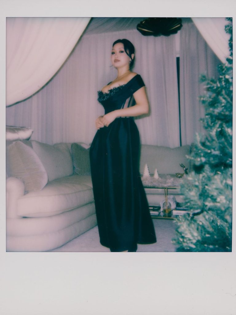Polaroid picture of Asian woman standing at a side angle and wearing a fancy dress