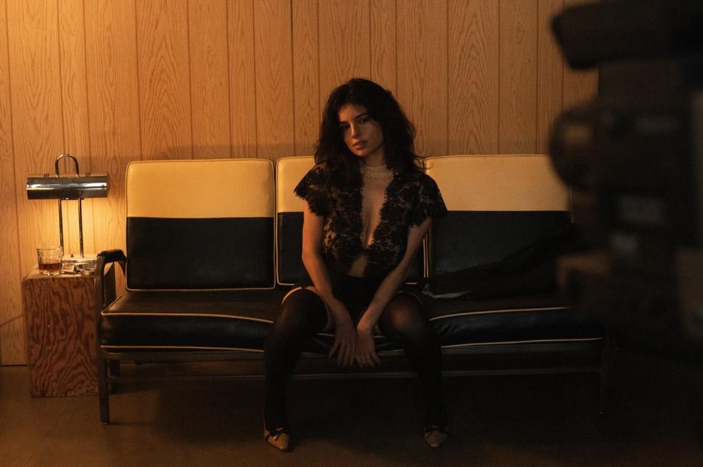 Far away frontal of woman wearing a lace top and sitting on leather sofa