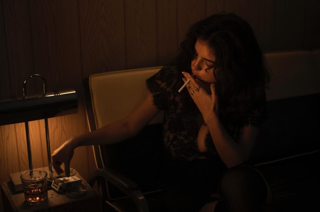 Looking down on a woman sitting in a chair and lighting a cigarette