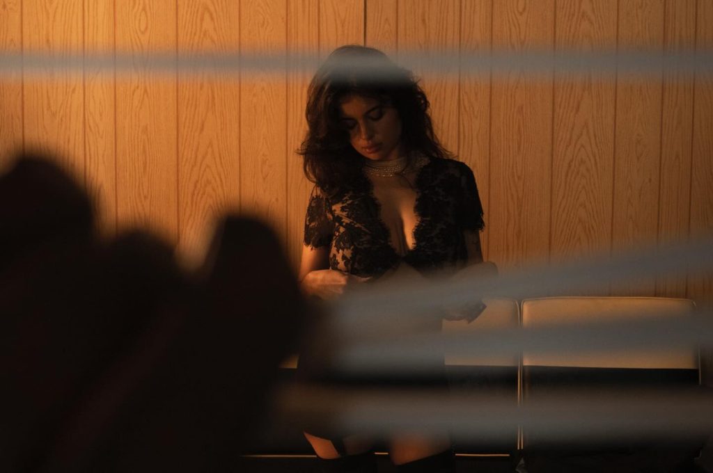 Looking through window blinds at a woman in a lace top