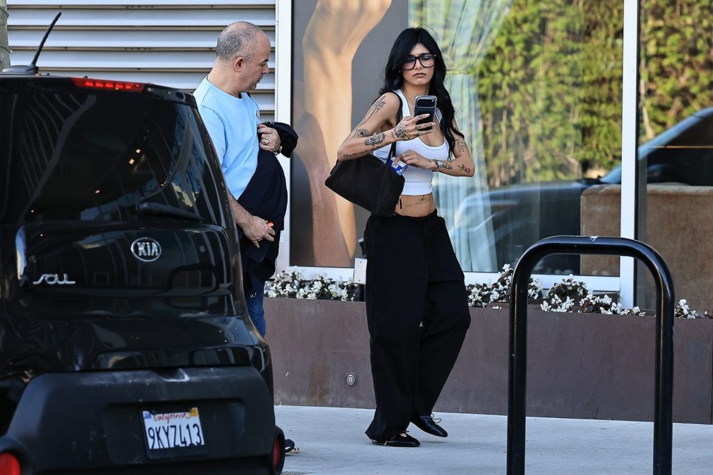 Far away view of man and woman walking on a sidewalk next to a parked car