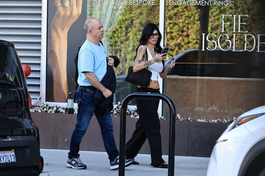 Woman looks at her phone as she walks along a sidewalk next to a man