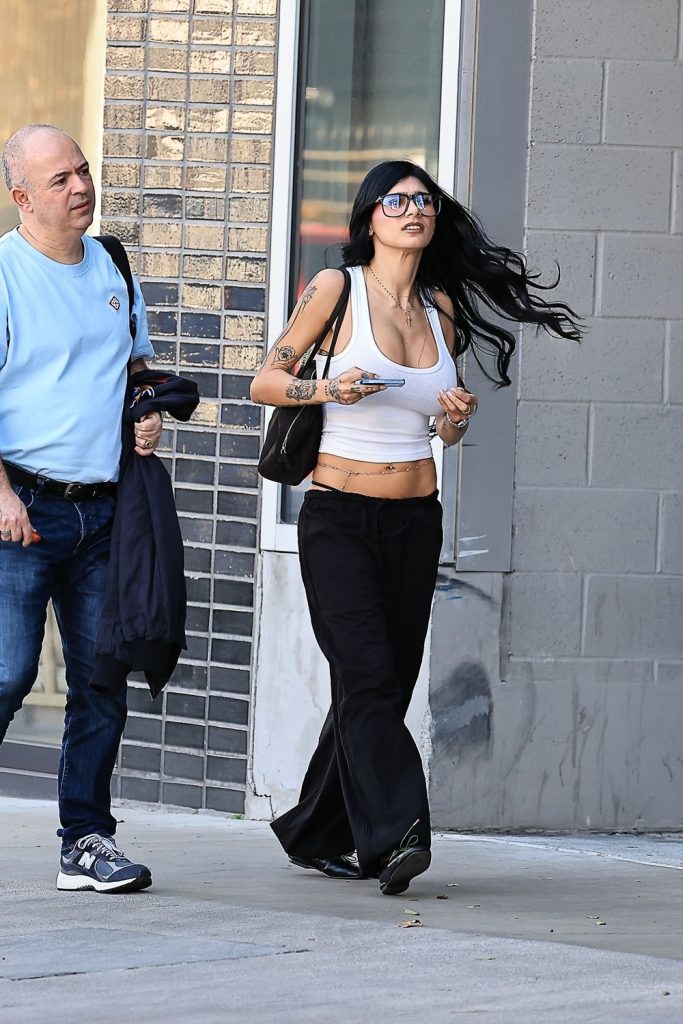 Closer view of the woman who is wearing pants and a tight tank top and glasses