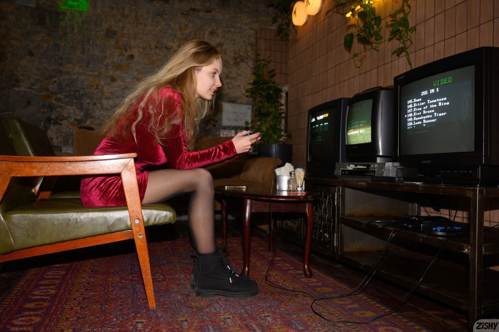 Far away side view of girl sitting down and playing a video game
