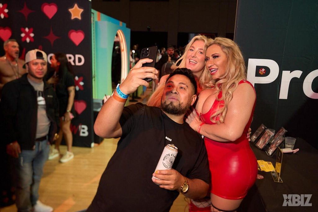 A fan snapping a selfie by the breasts of a porn star