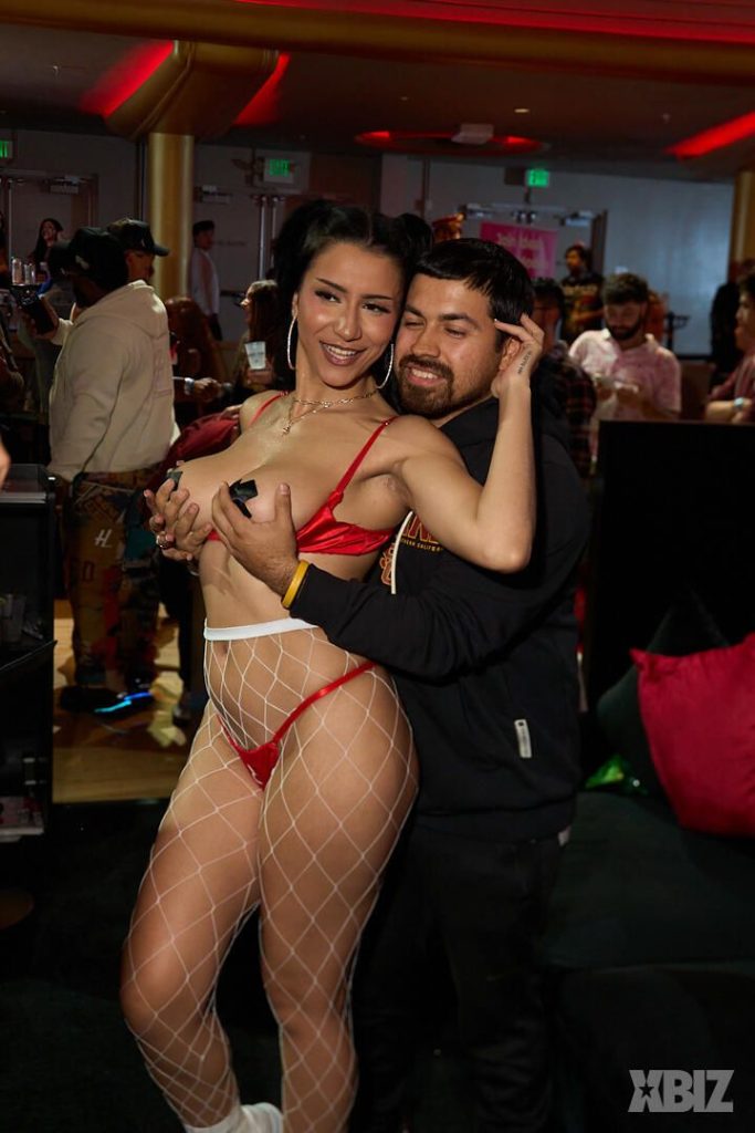 A fan reach around and grab the breasts of a smiling porn star at a convention