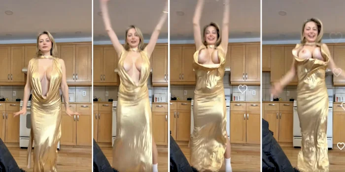 A woman in a shiny gold dress dances energetically in a kitchen, with the dress shifting and revealing more of her chest as she moves. The background shows light wood cabinets and kitchen appliances.